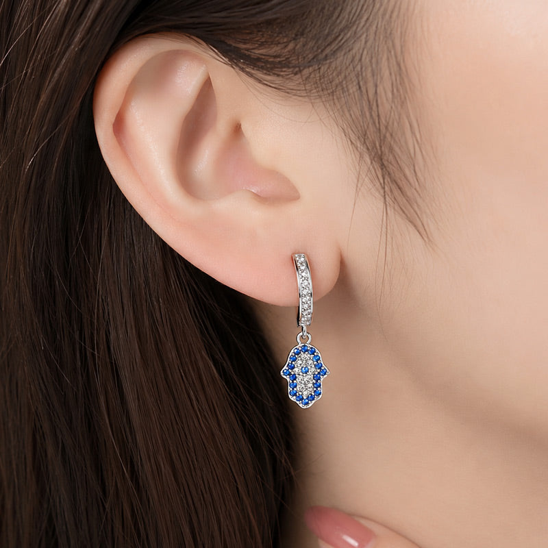 Modelo usando aretes Mano de Hamsa en Plata 925 con zirconias azules de Musas Vanidosas.